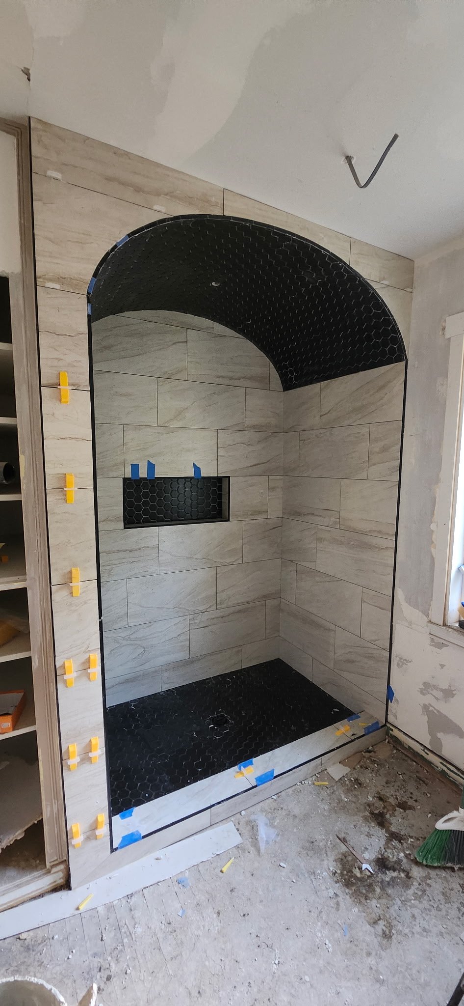 Arched shower with black hex tile and stone surround