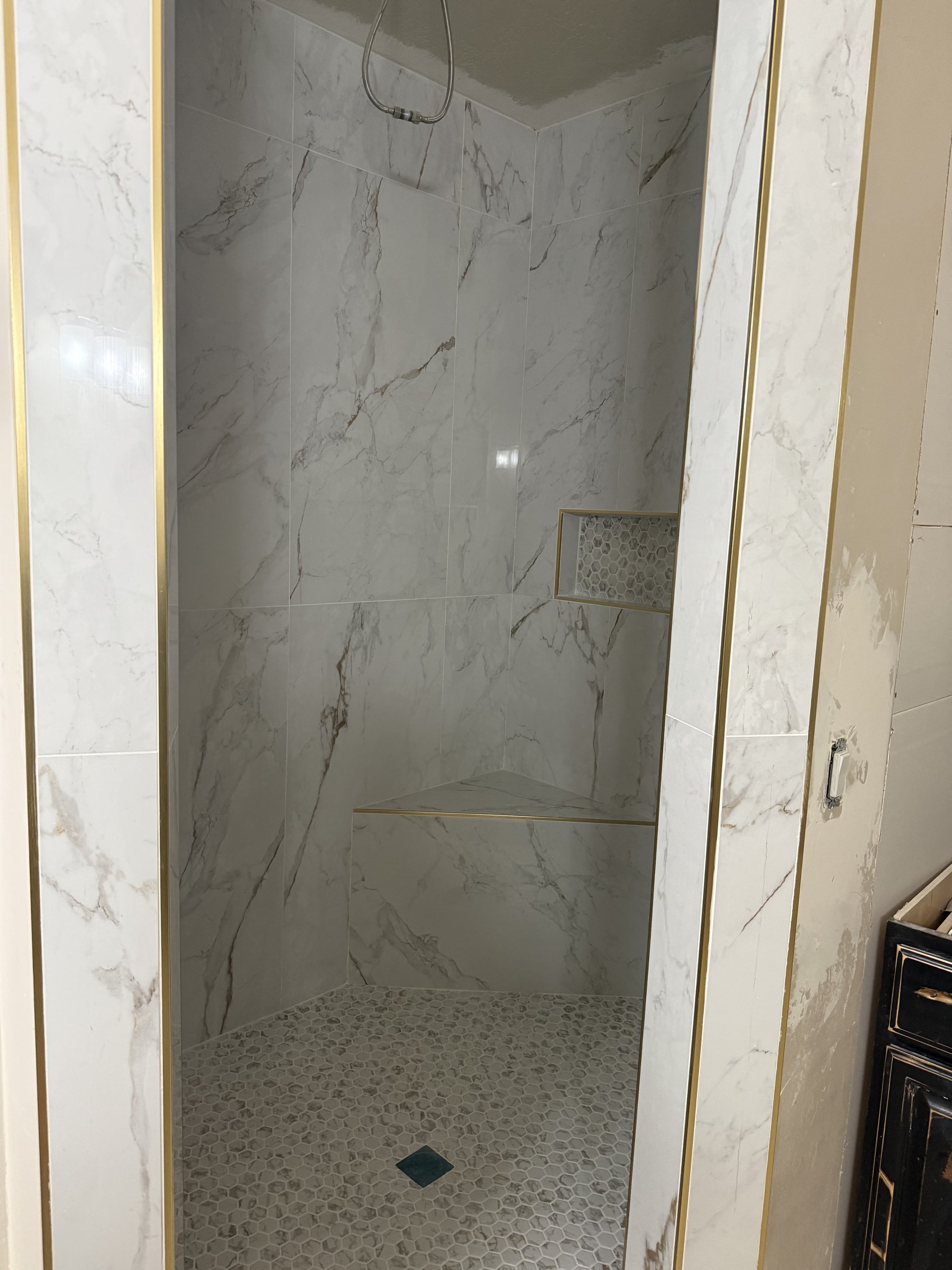 Framed marble shower walls with gold trim