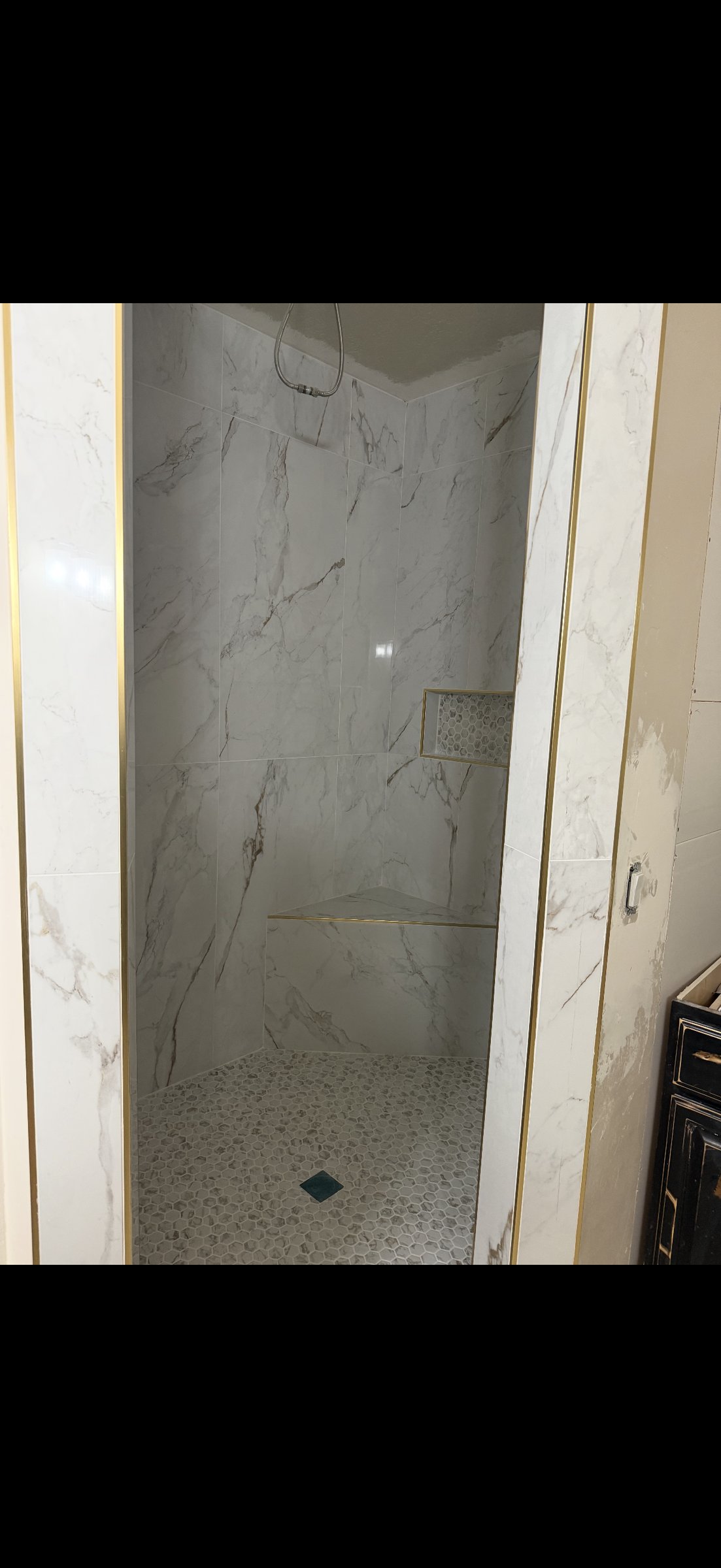 Marble shower with gold trim accents