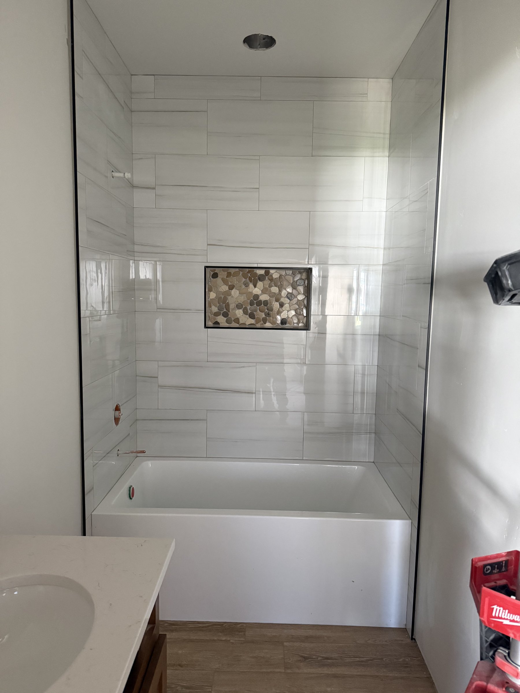 Marble tile shower with pebble niche