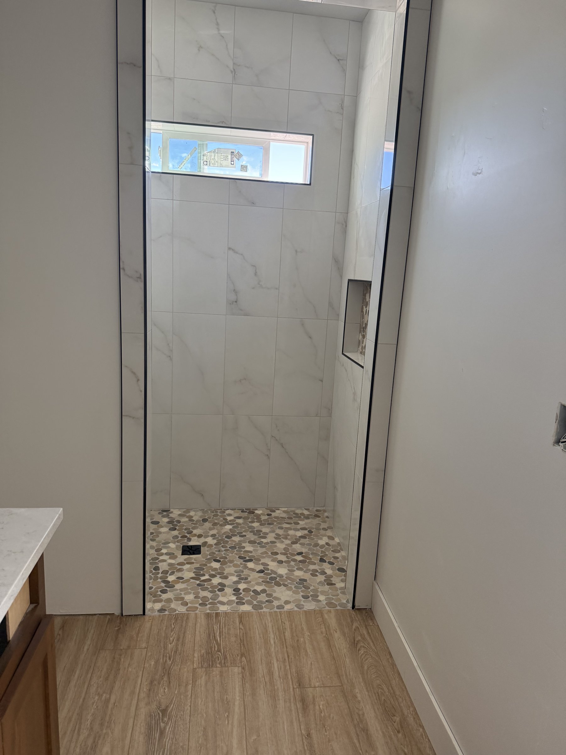 Marble shower with window and pebble accent
