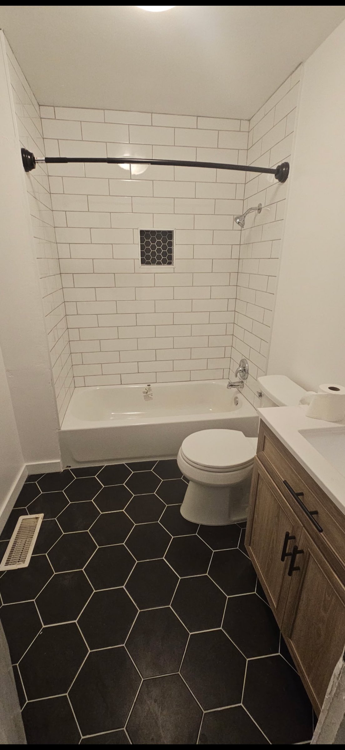 White subway tile shower with black hex floor