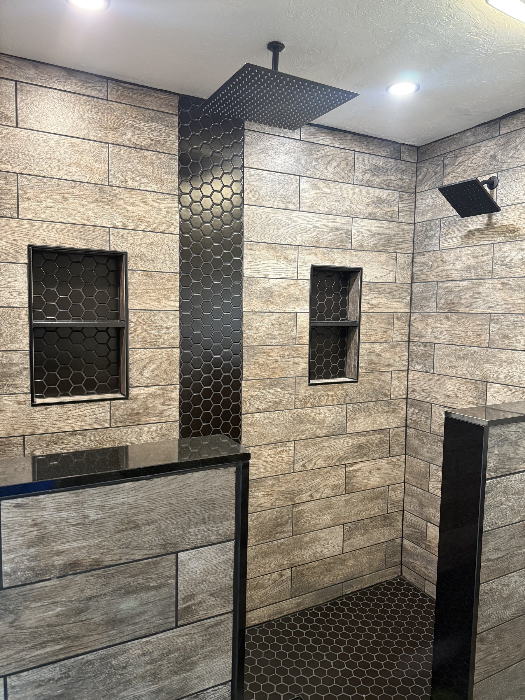 Wood look tile shower with black hex inlay
